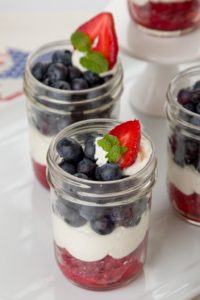 4oz mason jar with fresh strawberries, whip topping and blueberries.