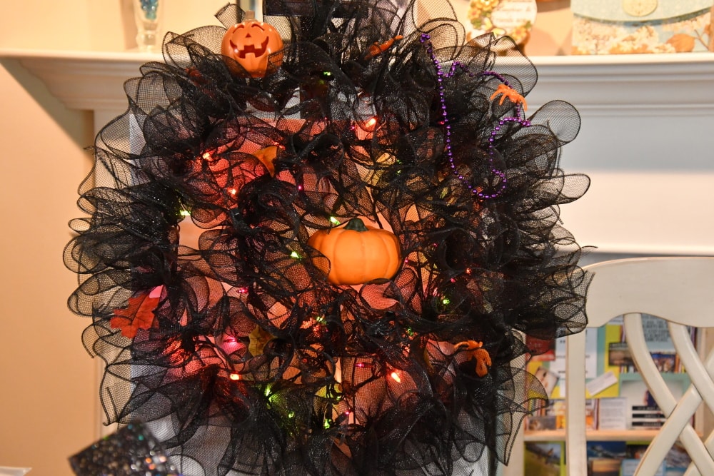 Easy Halloween wreath semi decorated: purple, green, orange lights and decorations.