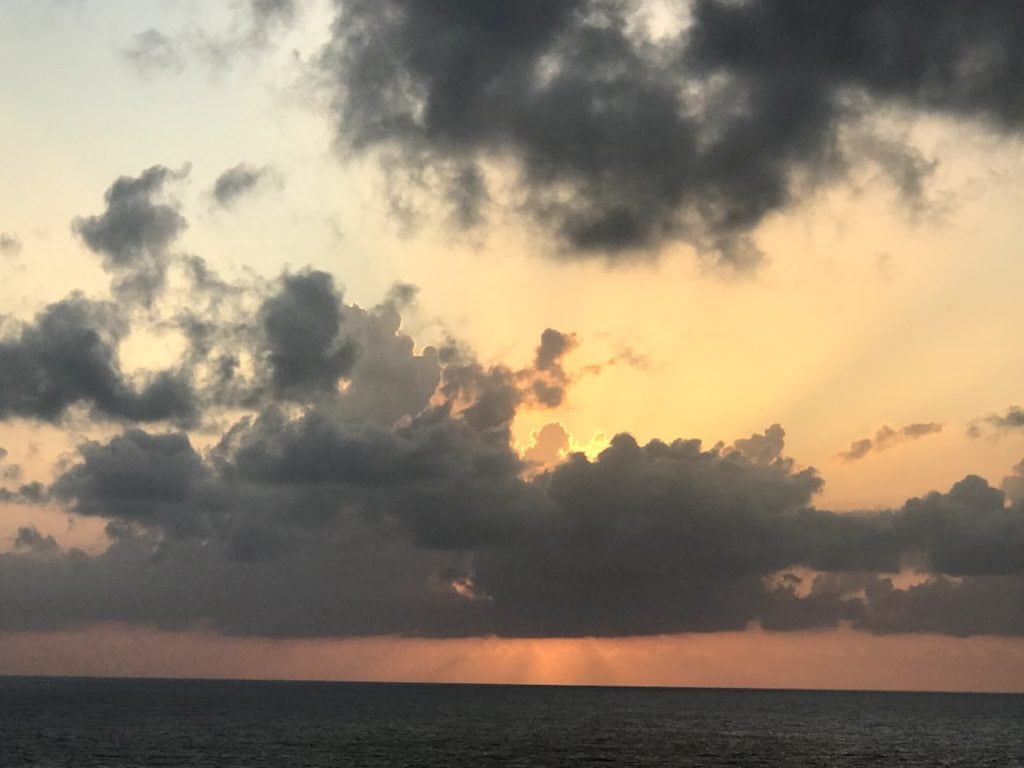 Sunset at the Mediterranean Sea with clouds, shades of coral and gray.