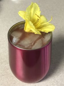Fruity Vodka Cocktail in an insulated cup ready to drink with a daylily garnish.