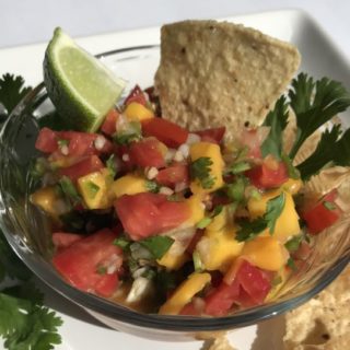 Fresh mango salsa with chip and lime.