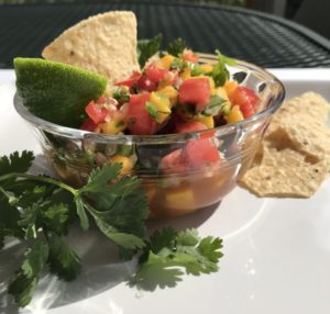 bowl of mango salsa with cilantro, lime and chips on the patio.