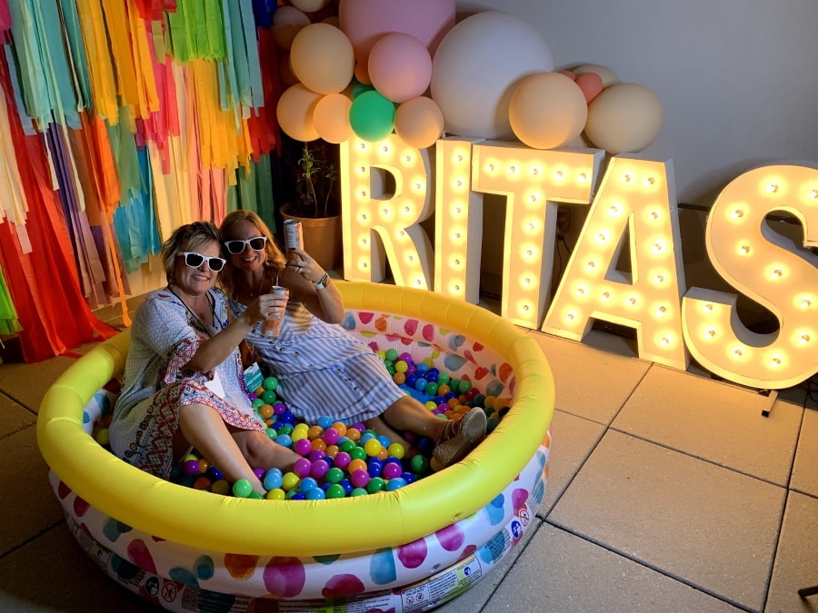 Trina and Megan at the hospitality suite posing in kiddie pool with pros for "rita's"