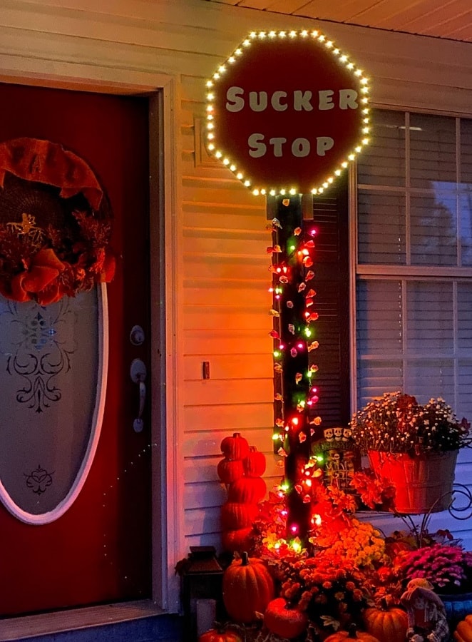 Front porch decorated with DIY Sucker Stop sign, pumpkins and mums.