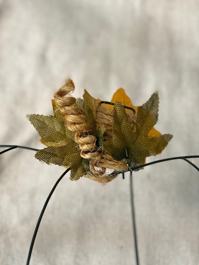 Dollar Tree Pumpkin wire frame with stem wrapped with twine and leaves.