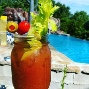 A Bloody Mary cocktail in a mason jar setting poolside ready to drink.