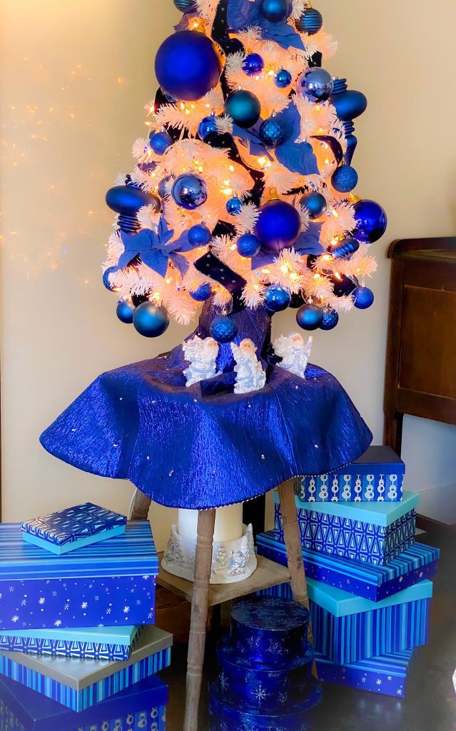 Beautiful white 4ft tree on a rustic wood table with blue and white lights and decorations on and around it.